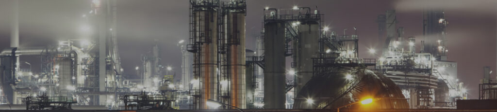 Panoramic image of a modern oil refinery facility with distillation towers and industrial processing equipment.