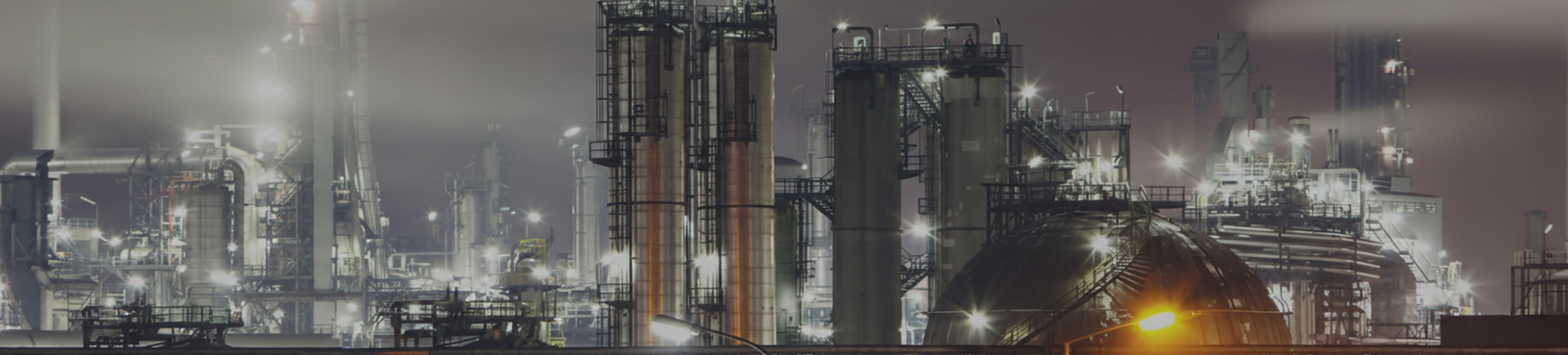 Panoramic image of a modern oil refinery facility with distillation towers and industrial processing equipment.